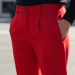 Zbliżenie na czerwone spodnie z widoczną fakturą tkaniny na tle rozmytego miejskiego otoczenia