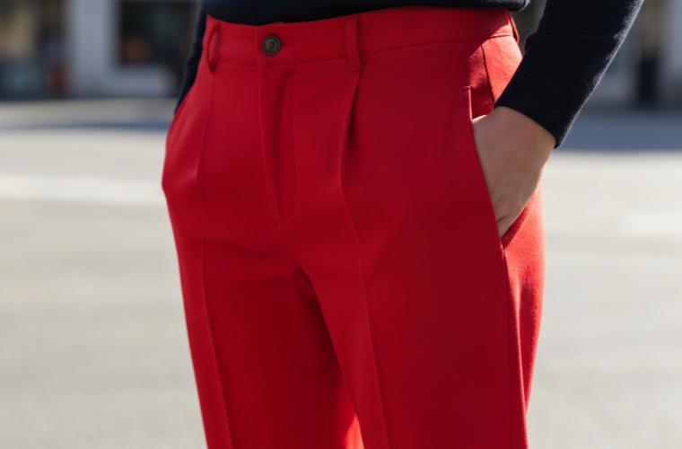 Zbliżenie na czerwone spodnie z widoczną fakturą tkaniny na tle rozmytego miejskiego otoczenia