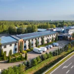 Hotel 500 Stryków otoczony zielenią, widok z lotu ptaka na budynek hotelu i drogę dojazdową.