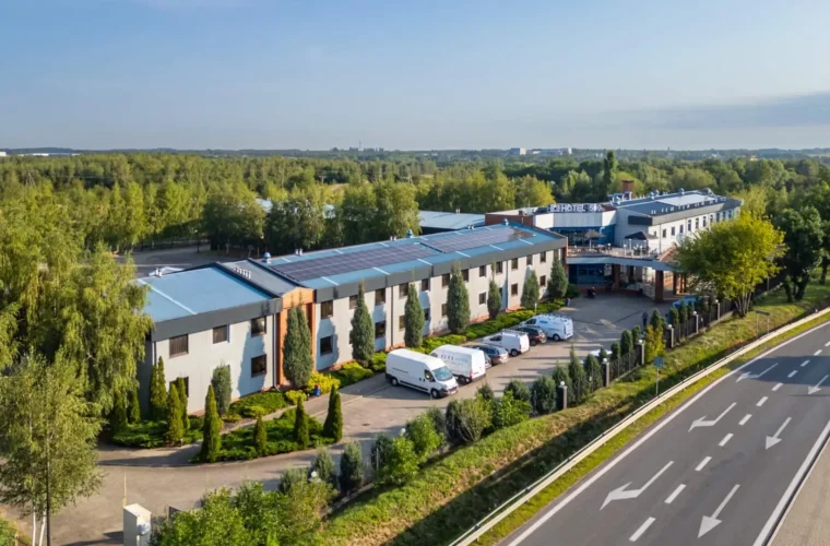 Hotel 500 Stryków otoczony zielenią, widok z lotu ptaka na budynek hotelu i drogę dojazdową.